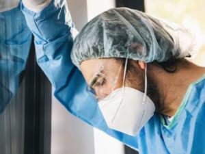 Health worker with mask looking exhausted.