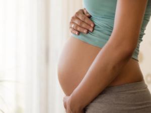 Pregnant's woman touching her belly with her hands.