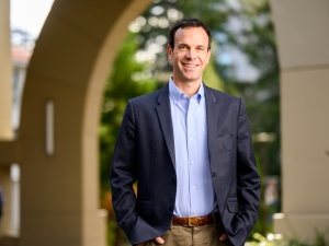 headshot of man standing in front of building